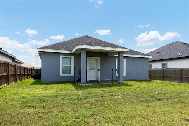 rear view of property featuring a fenced backyard, stucco siding, and a yard