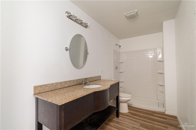 420 N Beto Garcia Dr, Weslaco, TX 78596 - full bathroom featuring vanity, tiled shower, wood finished floors, and toilet