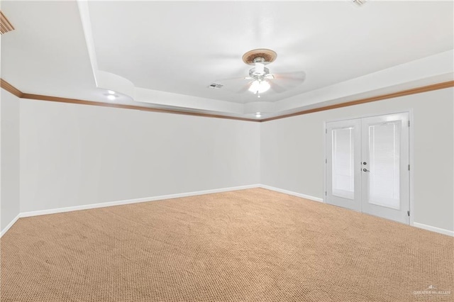 empty room with carpet flooring, ornamental molding, french doors, and a tray ceiling