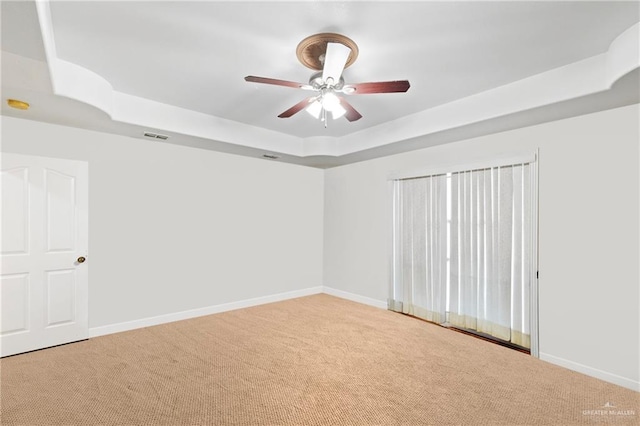 unfurnished room with light carpet, ceiling fan, and a tray ceiling