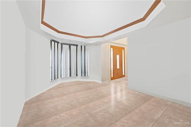 tiled spare room with crown molding and a tray ceiling