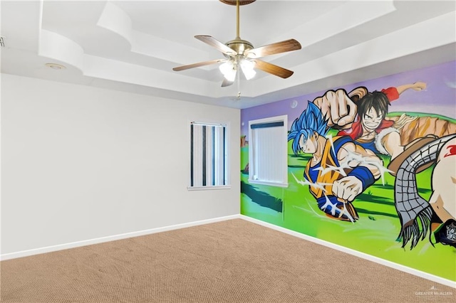 game room with carpet floors, ceiling fan, and a tray ceiling