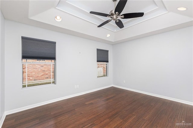 unfurnished room featuring ceiling fan, dark hardwood / wood-style flooring, and a raised ceiling