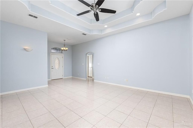 empty room with a tray ceiling, ceiling fan with notable chandelier, and light tile patterned flooring