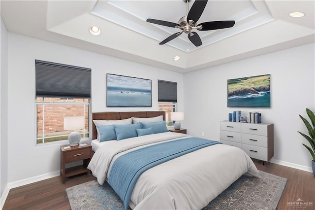 bedroom with dark hardwood / wood-style flooring, a tray ceiling, and ceiling fan