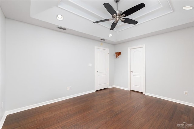 unfurnished room with ceiling fan, dark hardwood / wood-style floors, and a raised ceiling