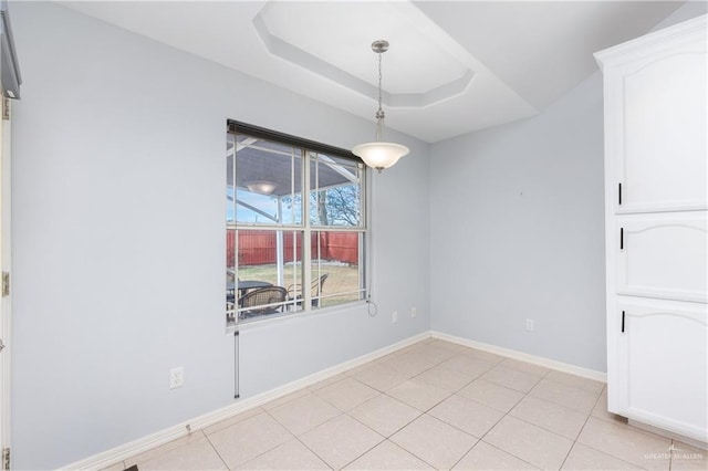 unfurnished dining area with light tile patterned flooring and a tray ceiling