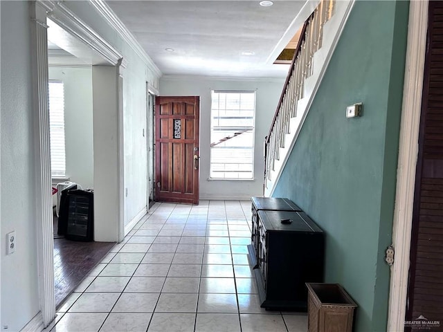 entrance foyer with light tile patterned floors, stairway, and crown molding