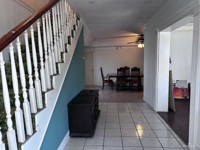 interior space with stairs, ornamental molding, baseboards, and light tile patterned floors