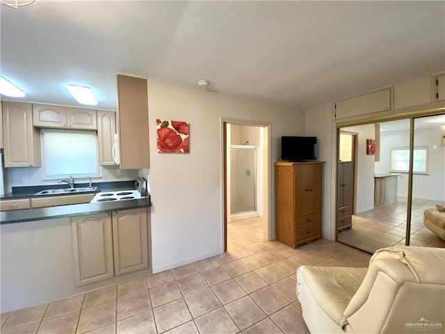 kitchen featuring a healthy amount of sunlight, electric range oven, sink, and light tile patterned floors