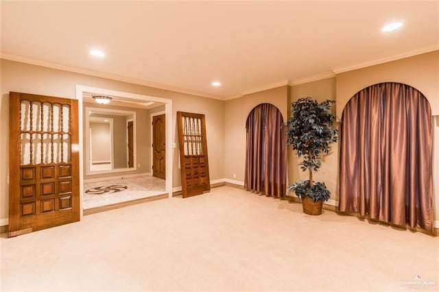 carpeted spare room featuring baseboards, recessed lighting, arched walkways, and crown molding