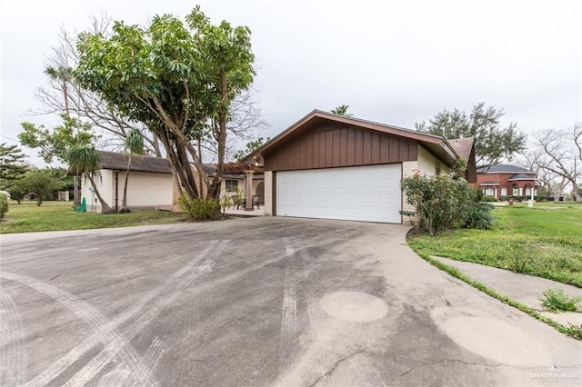 view of front of house featuring a front yard, concrete driveway, brick siding, and an attached garage