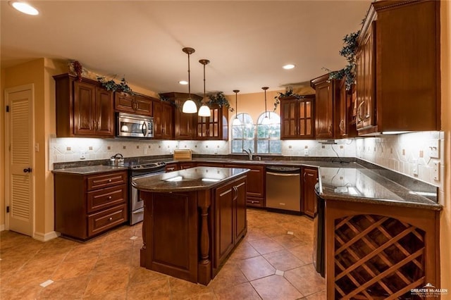 kitchen with stainless steel appliances, hanging light fixtures, decorative backsplash, glass insert cabinets, and a sink