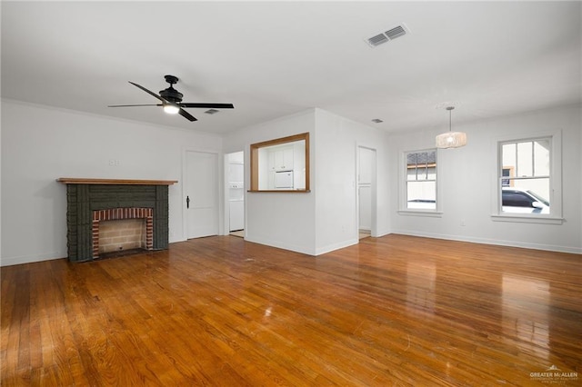 unfurnished living room featuring ceiling fan, hardwood / wood-style floors, and a brick fireplace