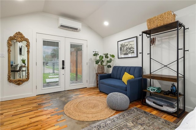 sitting room with vaulted ceiling, a wall unit AC, and french doors