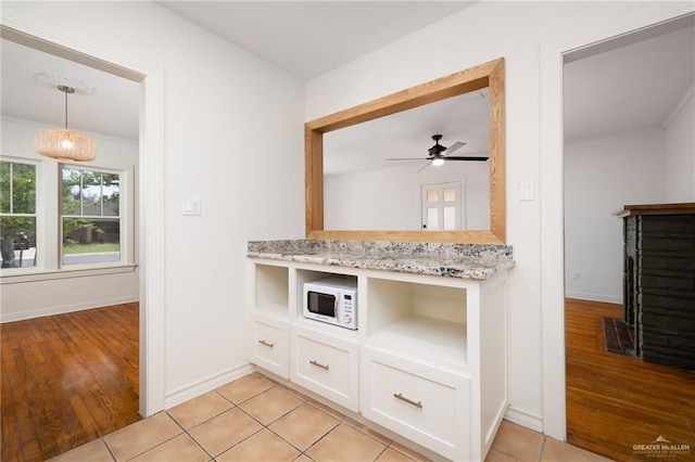 kitchen with light stone counters, ceiling fan, pendant lighting, light hardwood / wood-style floors, and white cabinetry