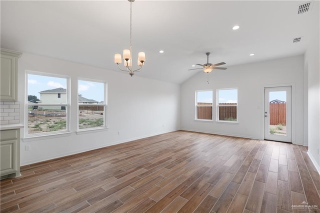 unfurnished living room with ceiling fan with notable chandelier, visible vents, and wood finished floors