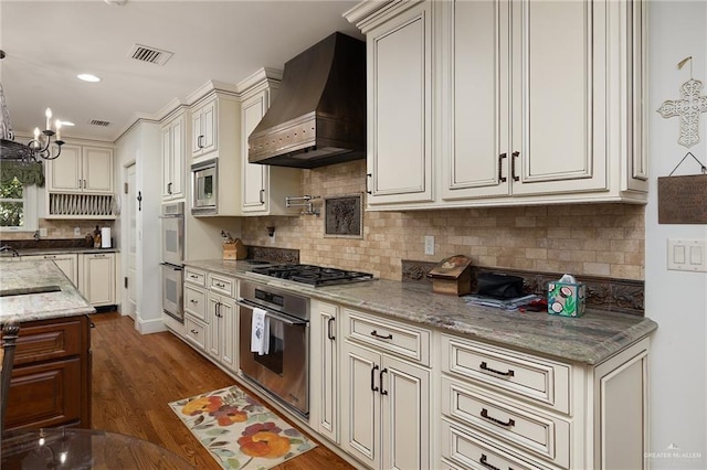 kitchen with premium range hood, pendant lighting, tasteful backsplash, stainless steel appliances, and light stone countertops