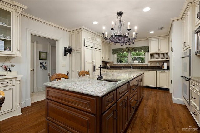 kitchen with sink, a kitchen island with sink, and cream cabinetry