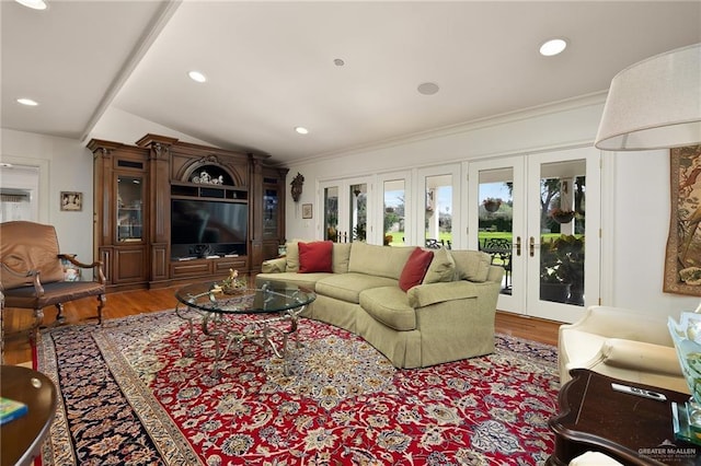 living room with ornamental molding, vaulted ceiling, hardwood / wood-style floors, and french doors