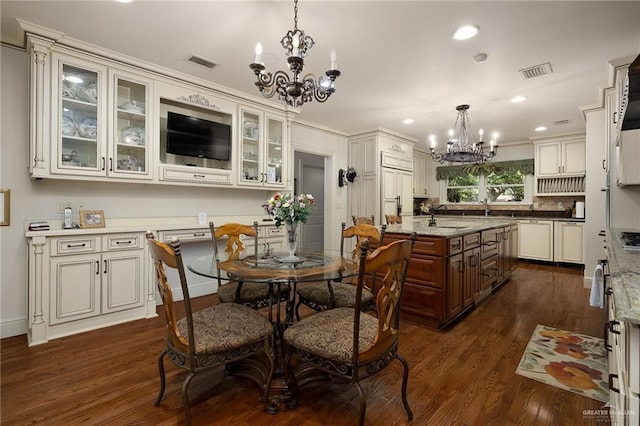 kitchen featuring dark hardwood / wood-style flooring, decorative light fixtures, a chandelier, and an island with sink