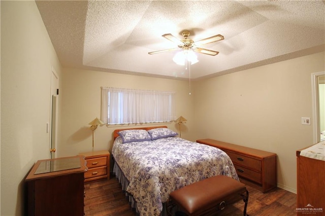 bedroom with dark wood-type flooring, ceiling fan, a raised ceiling, and a textured ceiling