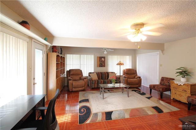 living room with dark tile patterned flooring, a textured ceiling, and ceiling fan