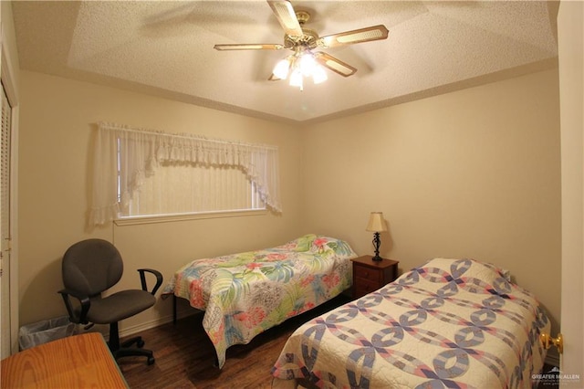 bedroom with ceiling fan, a textured ceiling, dark hardwood / wood-style flooring, and a closet