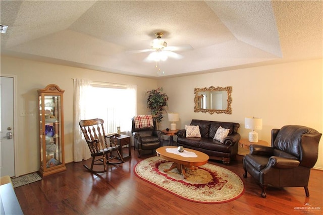 living room with dark hardwood / wood-style flooring, ceiling fan, a raised ceiling, and a textured ceiling