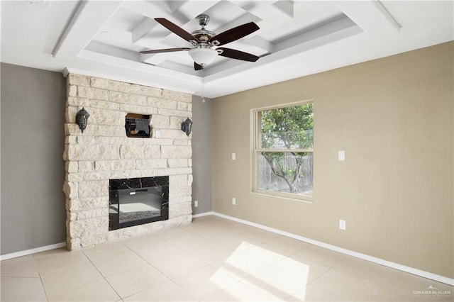 unfurnished living room with ceiling fan, light tile patterned floors, a fireplace, and a tray ceiling