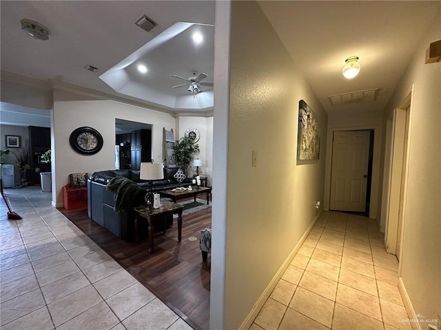 hallway featuring light tile patterned flooring and a raised ceiling