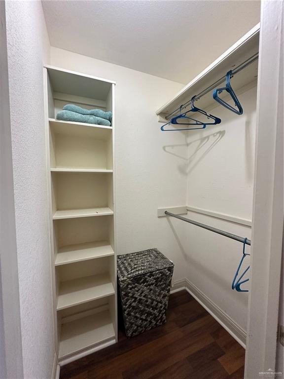 walk in closet with dark wood-type flooring