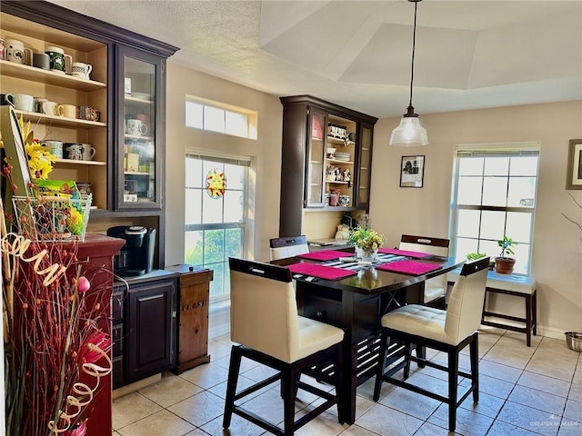 tiled dining area with a textured ceiling and a tray ceiling