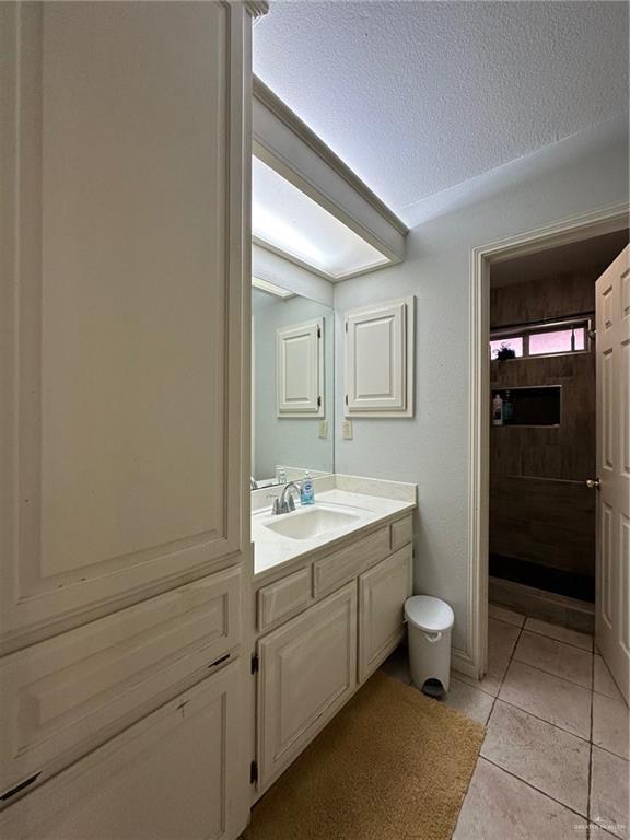 bathroom with a textured ceiling, tile patterned floors, and vanity