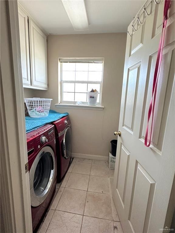 laundry room with light tile patterned flooring, washing machine and clothes dryer, and cabinets