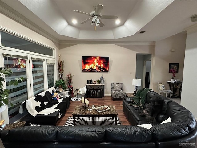 living room with ceiling fan, hardwood / wood-style floors, ornamental molding, and a raised ceiling