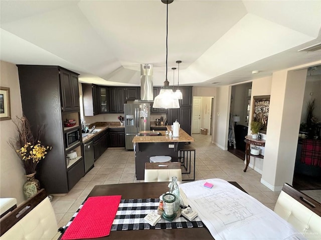 kitchen with stainless steel appliances, a center island, light tile patterned floors, dark brown cabinetry, and decorative light fixtures