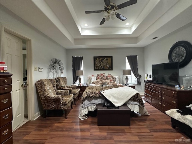 bedroom with ceiling fan, dark wood-type flooring, and a raised ceiling