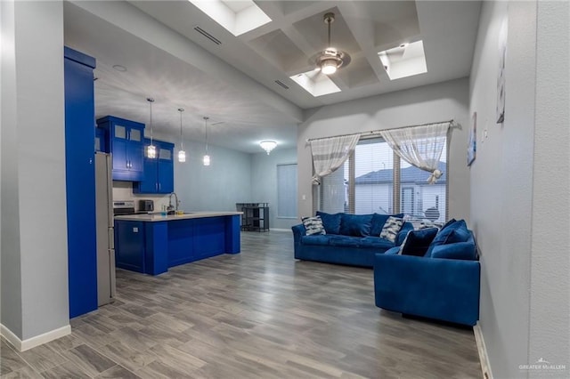 living room featuring hardwood / wood-style floors, a skylight, sink, coffered ceiling, and ceiling fan