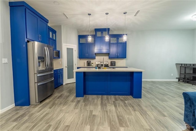 kitchen featuring a kitchen island with sink, stainless steel fridge with ice dispenser, hanging light fixtures, and blue cabinets