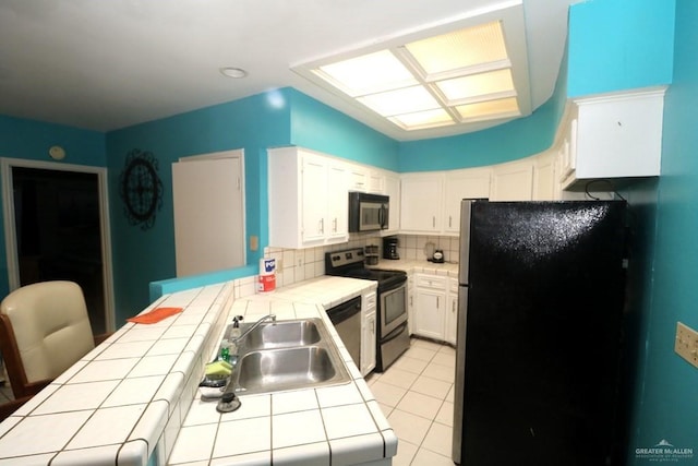 kitchen with stainless steel appliances, white cabinetry, sink, and tile counters