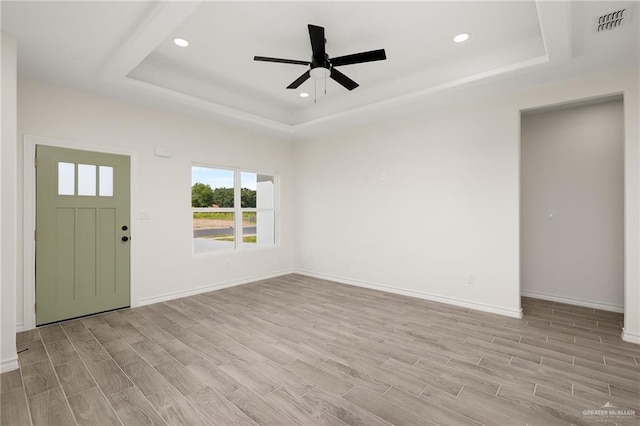 interior space with ceiling fan, light hardwood / wood-style floors, and a tray ceiling