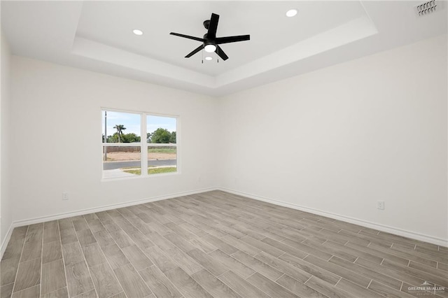 spare room featuring light hardwood / wood-style floors, a raised ceiling, and ceiling fan