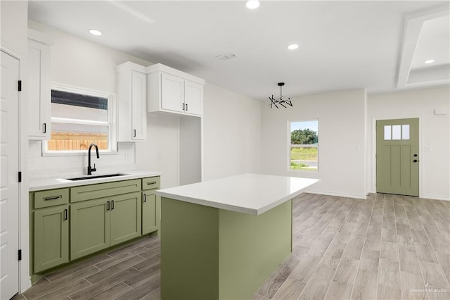 kitchen with white cabinets, light hardwood / wood-style flooring, a kitchen island, and sink