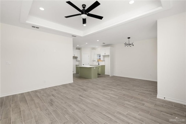 unfurnished living room with a tray ceiling and light hardwood / wood-style flooring