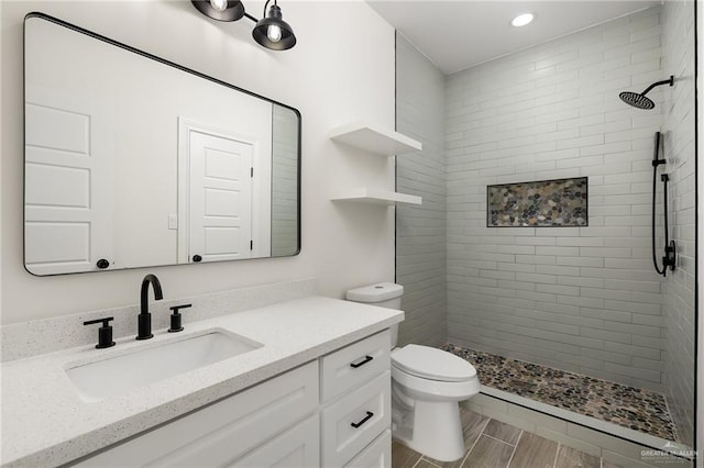 bathroom featuring vanity, toilet, and tiled shower