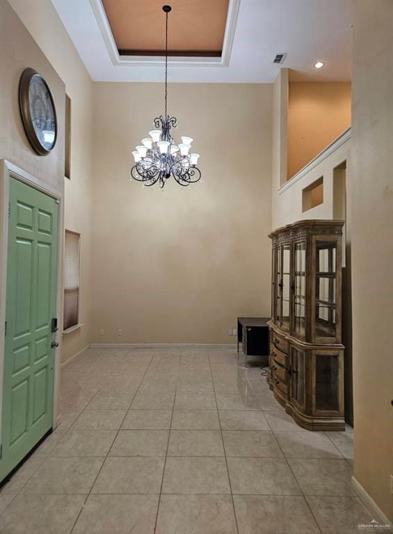 3109 S Casa Linda St, Mcallen, TX 78503 - foyer featuring a high ceiling, a chandelier, a tray ceiling, baseboards, and light tile patterned floors