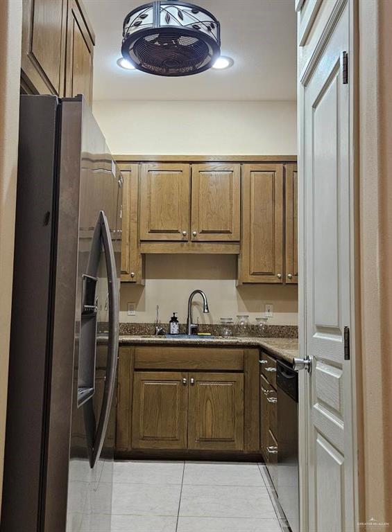 3109 S Casa Linda St, Mcallen, TX 78503 - kitchen featuring appliances with stainless steel finishes, a sink, light tile patterned floors, dark countertops, and brown cabinetry