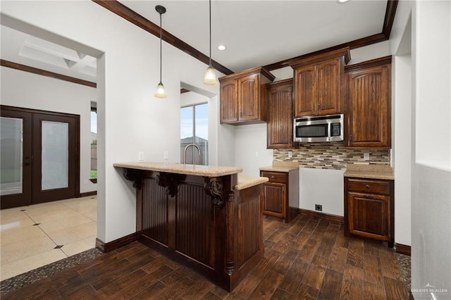 kitchen featuring decorative light fixtures, dark hardwood / wood-style flooring, a kitchen bar, and crown molding