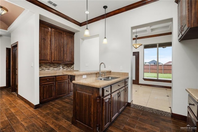 kitchen featuring dark wood-type flooring, sink, decorative backsplash, light stone counters, and dark brown cabinetry